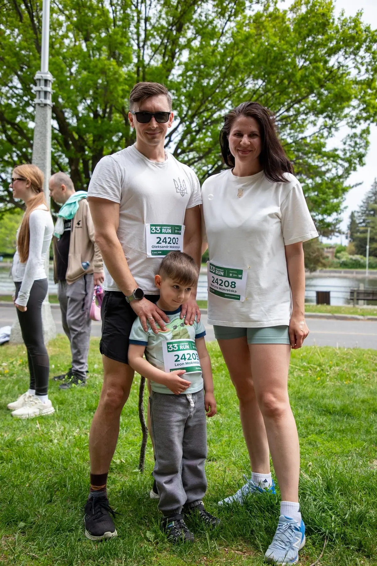 A family of three wearing Chestnut Run bibs on the grass before the start