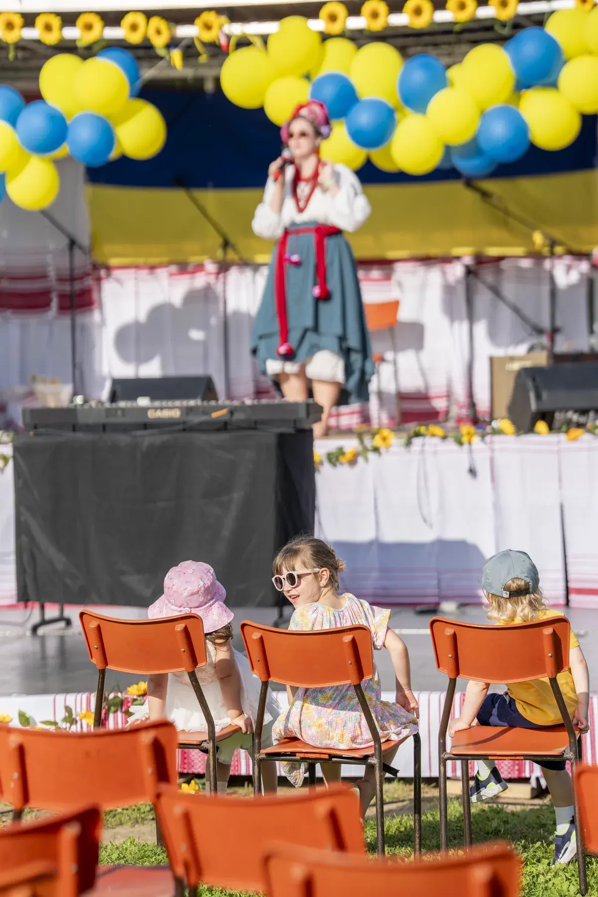 Olga Ostafiichuk at UAFest 2026 — Children on orange chairs watching the host sing on the decorated stage (photo: Tim Skinner)