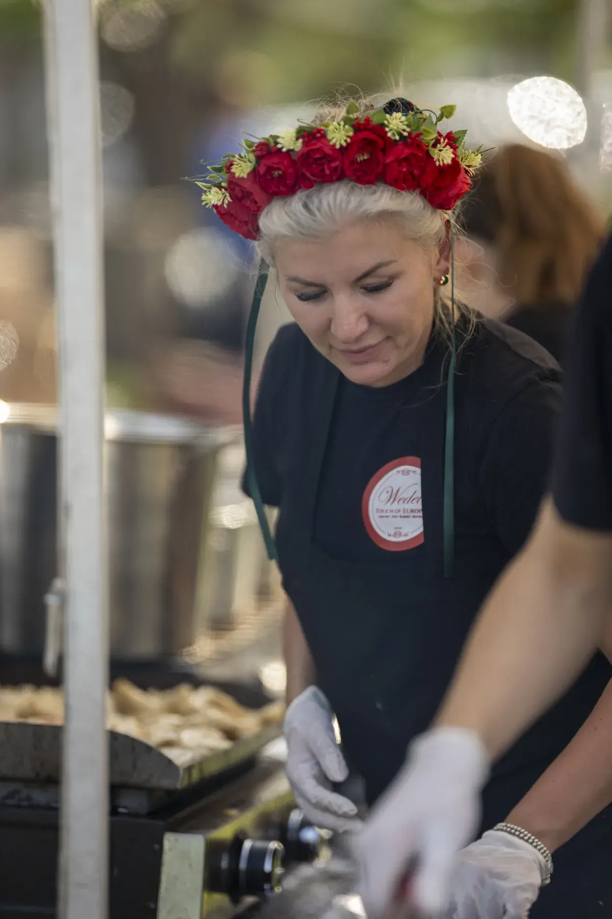 Wedel — Touch of Europe at UAFest 2026 — Cook in a red flower crown prepares food at a grill (photo: Tim Skinner)