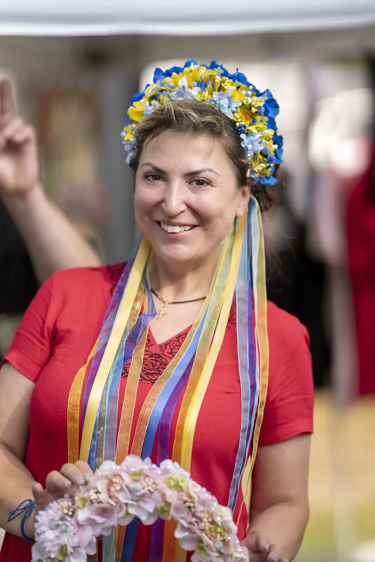 Smiling woman in a blue-yellow flower crown with ribbons and a floral wreath