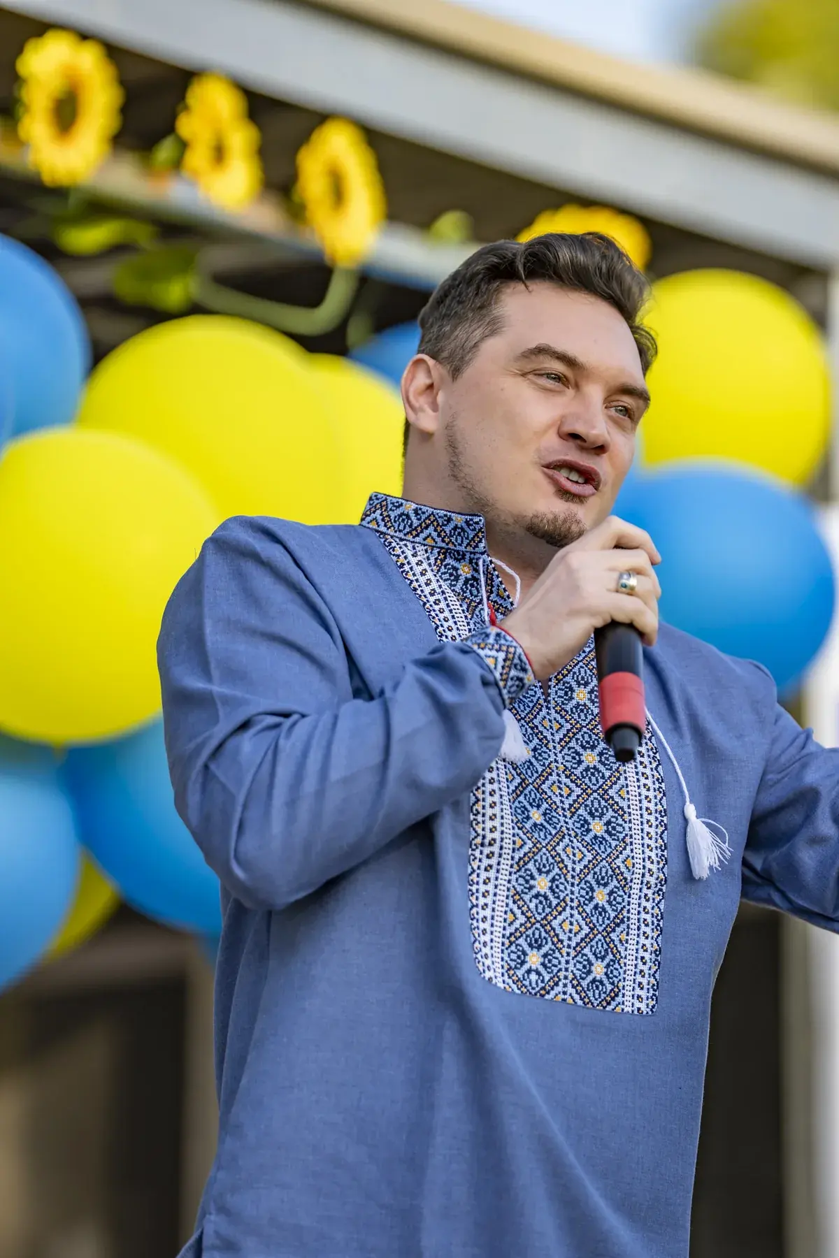 DEN BAURIN at UAFest 2026 — Male singer in a blue embroidered shirt performs in front of balloons (photo: Tim Skinner)