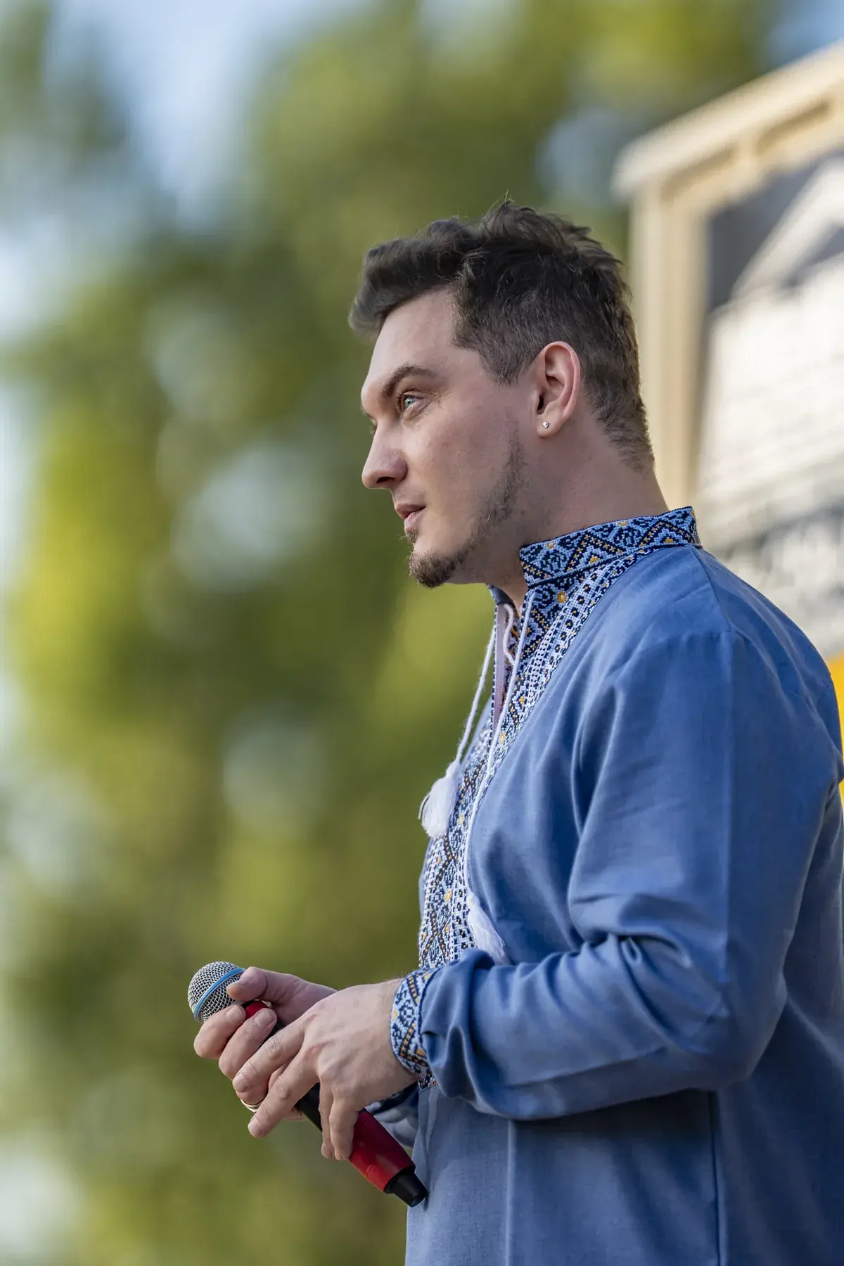 DEN BAURIN at UAFest 2026 — Male singer in a blue vyshyvanka pauses in profile, holding the microphone (photo: Tim Skinner)
