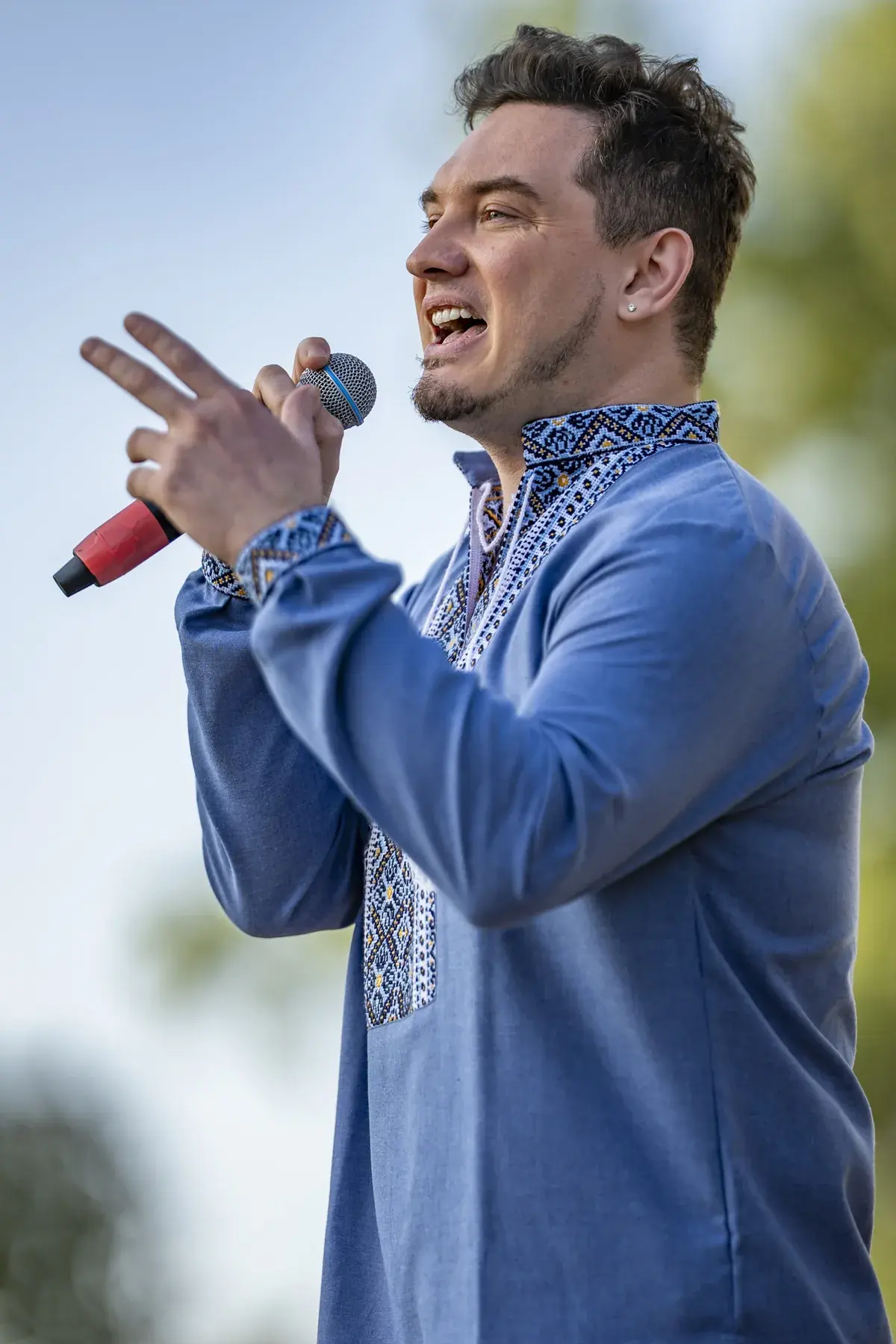DEN BAURIN at UAFest 2026 — Male singer in a blue vyshyvanka sings with trees behind him (photo: Tim Skinner)