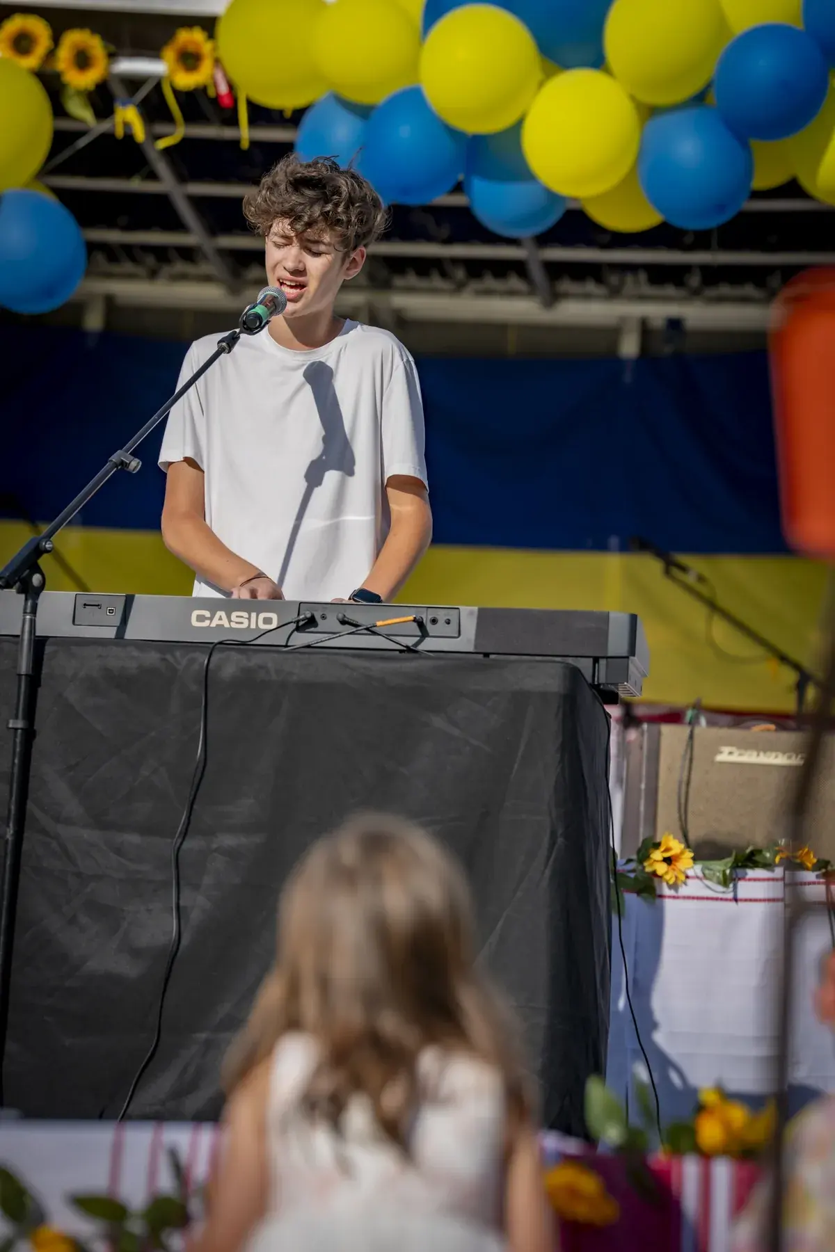 Ivan Horobets at UAFest 2026 — Teenage keyboardist on stage, a girl in a white dress watching in the foreground (photo: Tim Skinner)