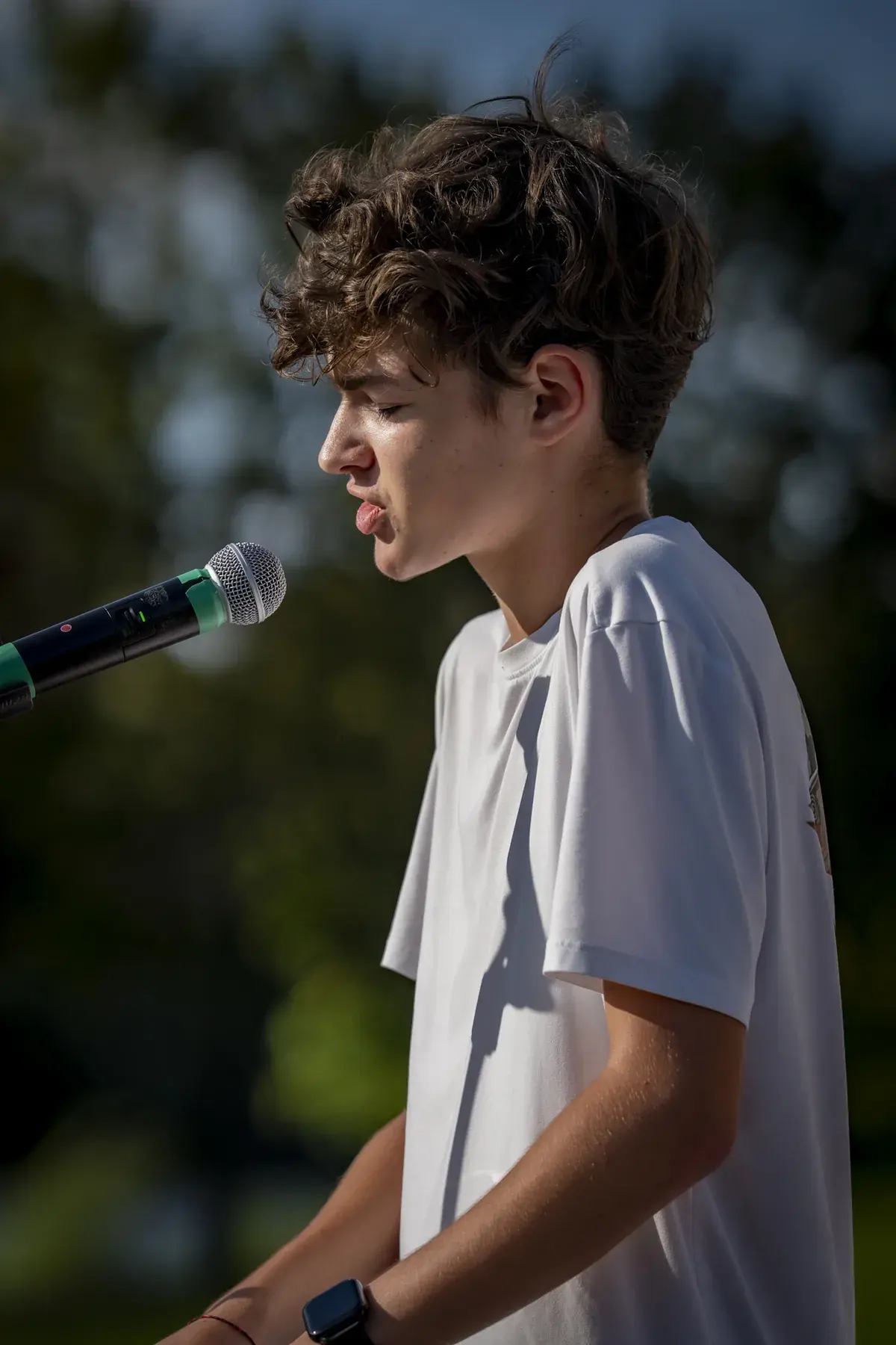Ivan Horobets at UAFest 2026 — Teenage performer singing at the keyboard, side view against greenery (photo: Tim Skinner)