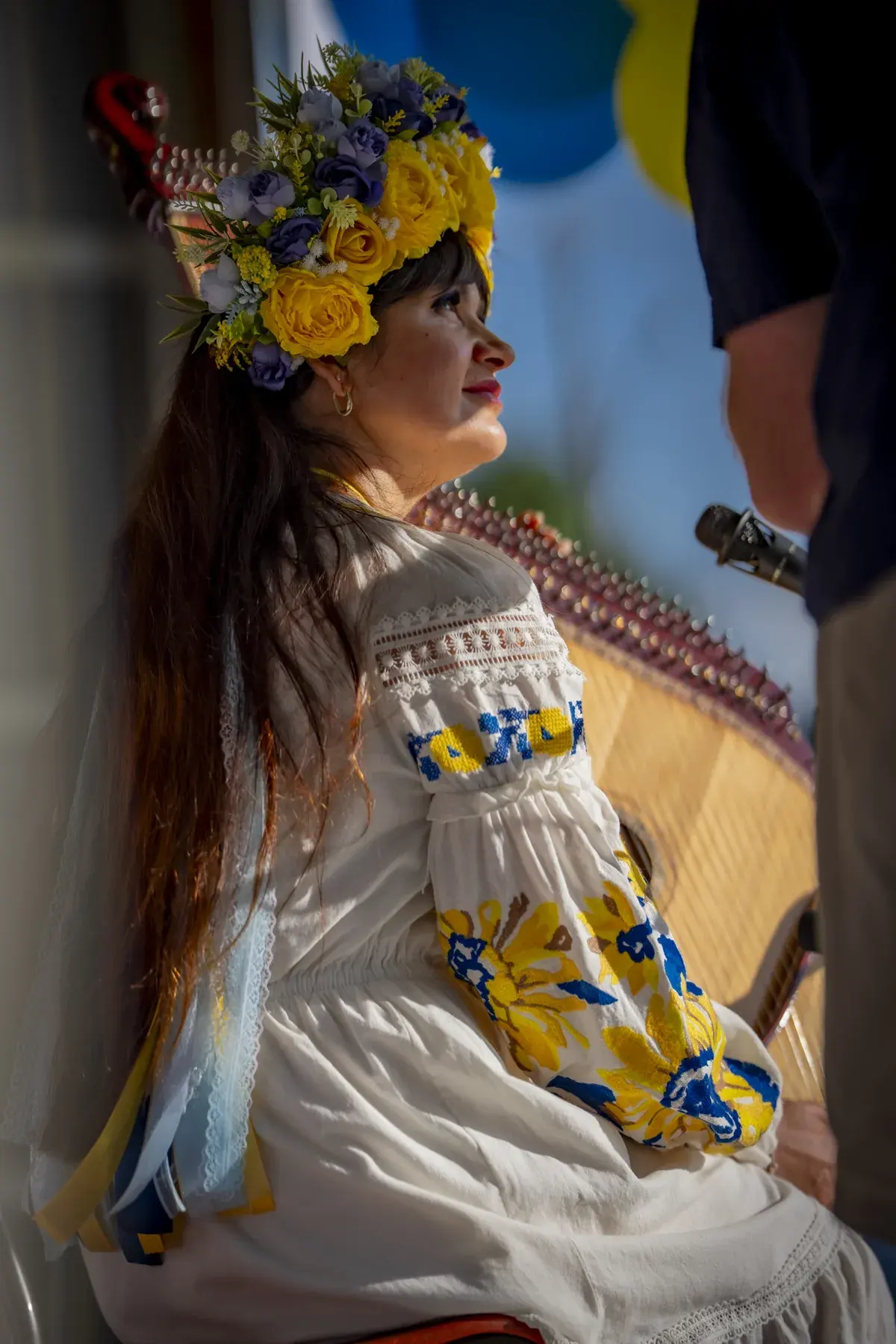 Lidiia Hurinenko at UAFest 2026 — Bandura player in a yellow-blue flower crown seated on stage, side view (photo: Tim Skinner)