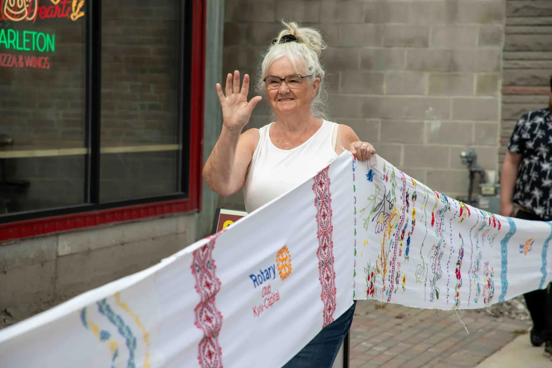 A participant waves while holding the embroidered cloth during the procession