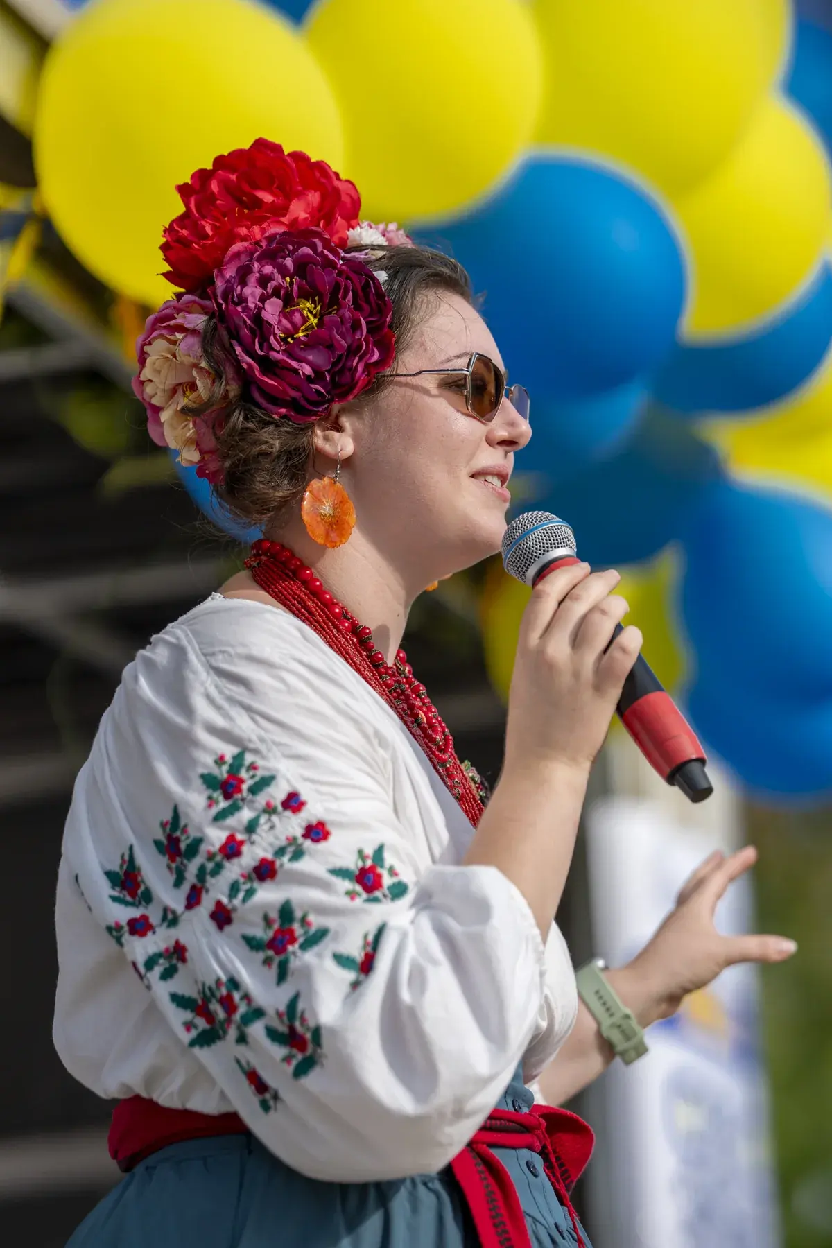 Host in a floral crown singing among blue and yellow balloons
