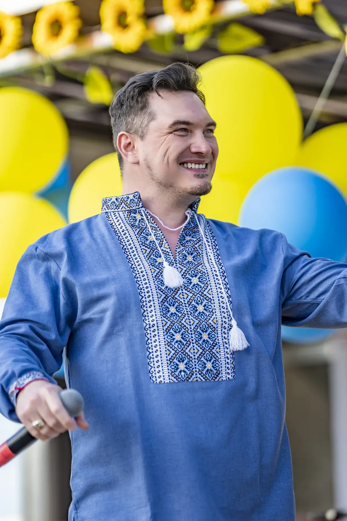 DEN BAURIN at UAFest 2026 — Smiling male singer in a blue vyshyvanka with yellow and blue balloons (photo: Tim Skinner)