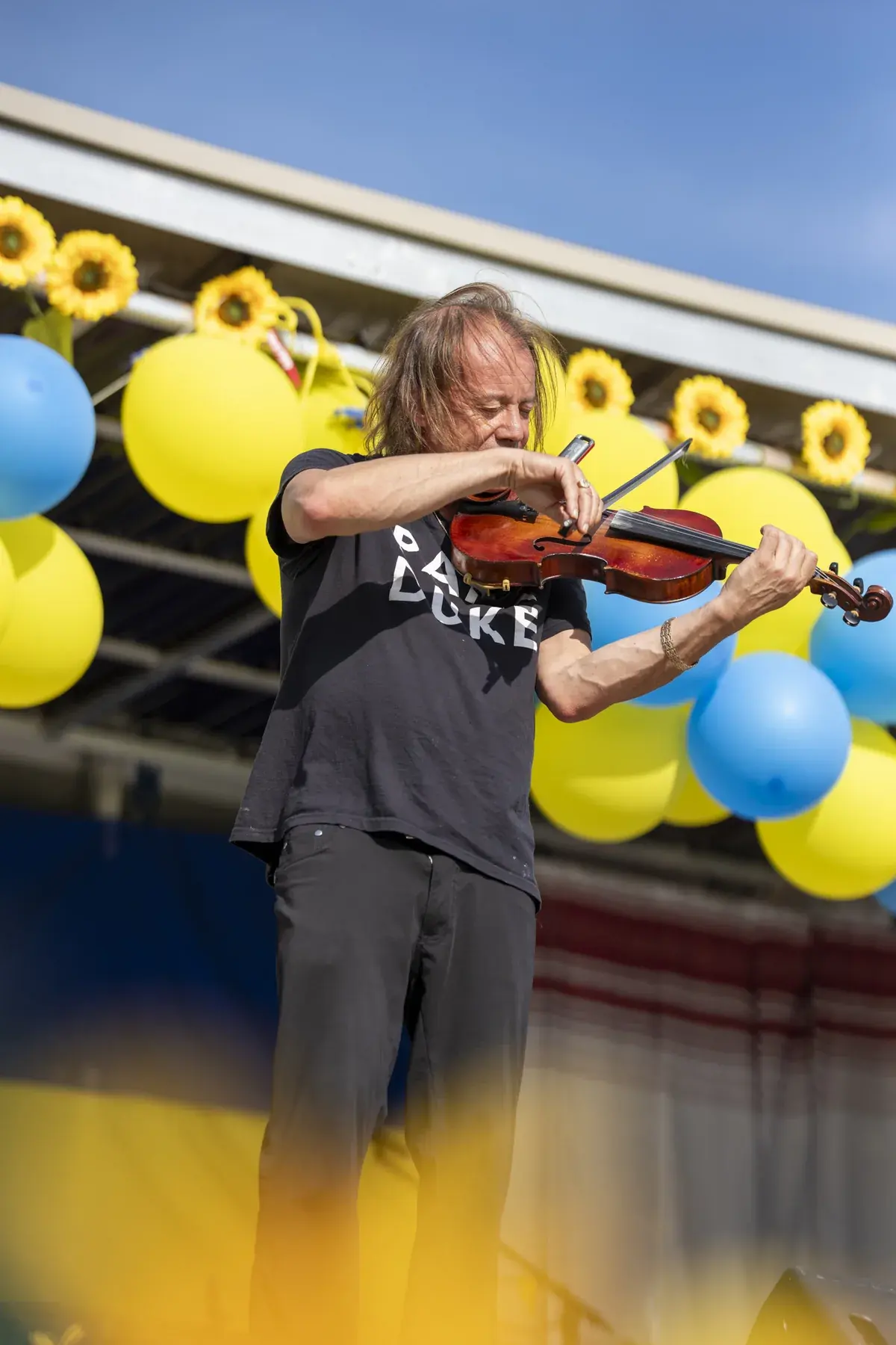 Vasyl Popadiuk at UAFest 2026 — Violinist on stage under sunflowers and yellow-blue balloons (photo: Tim Skinner)