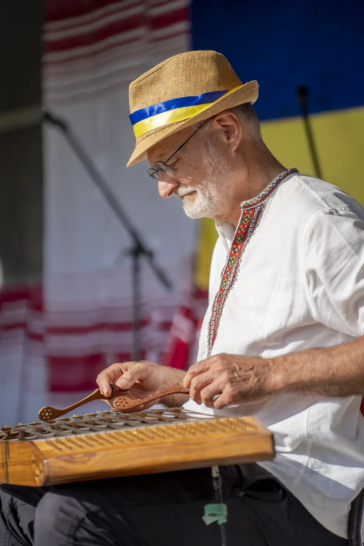 Roman Tykajlo at UAFest 2026 — Musician in a straw hat with a blue-yellow band playing a cymbaly on stage (photo: Tim Skinner)