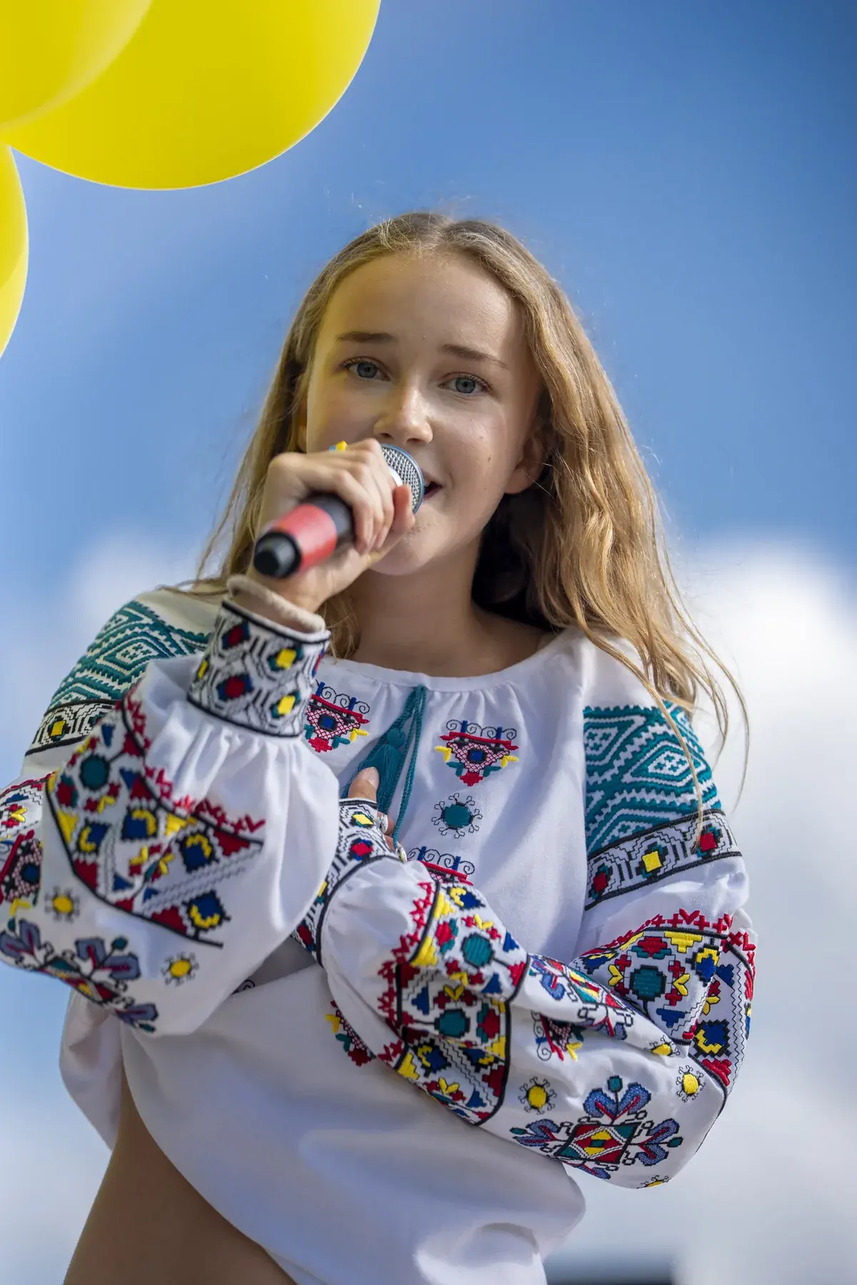 Marta Stepanenko at UAFest 2026 — Teen singer in vyshyvanka sings against a blue sky (photo: Tim Skinner)