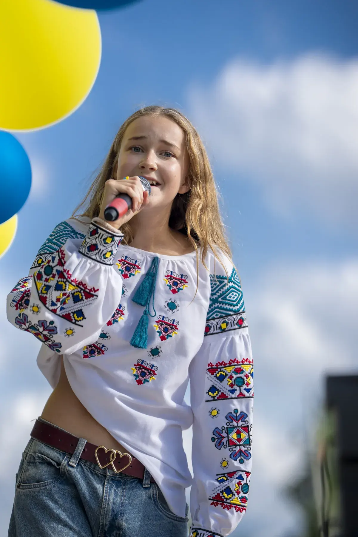Marta Stepanenko at UAFest 2026 — Teen singer in vyshyvanka sings against a blue sky (photo: Tim Skinner)