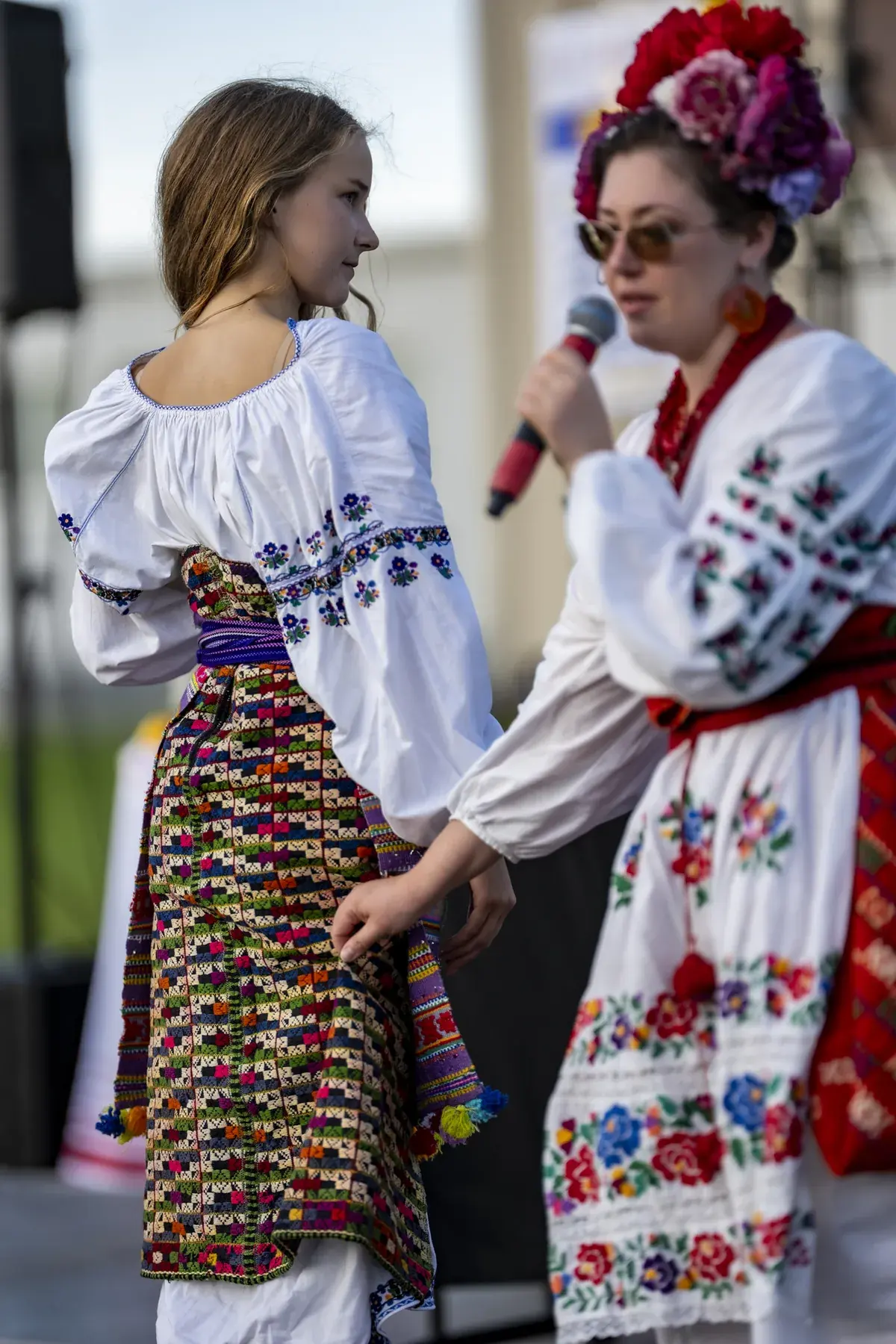 Olga Ostafiichuk at UAFest 2026 — Host with a microphone presents a girl's traditional costume, back view (photo: Tim Skinner)