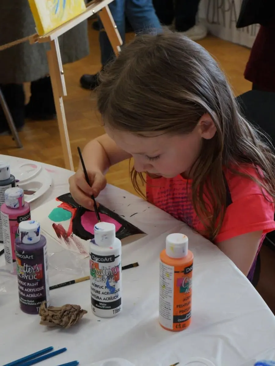 A child painting at an easel during an art workshop