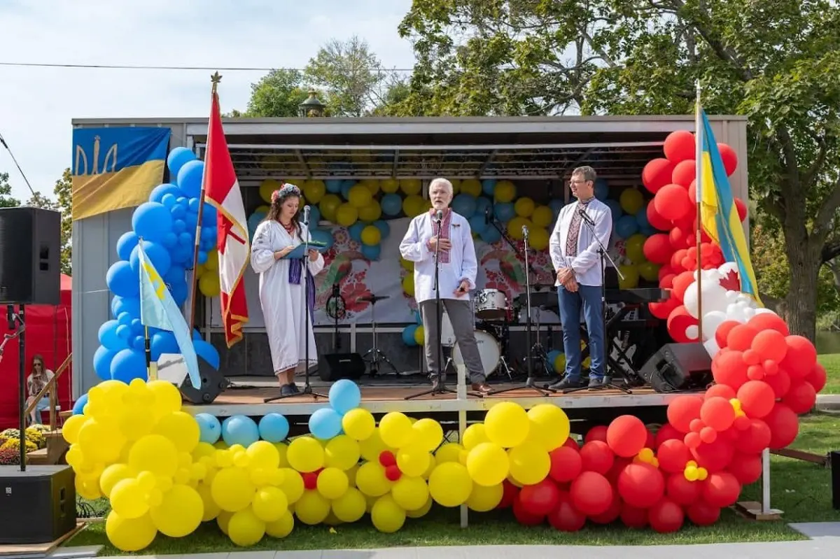 A performer in folk costume with a flag and balloons at UAFest