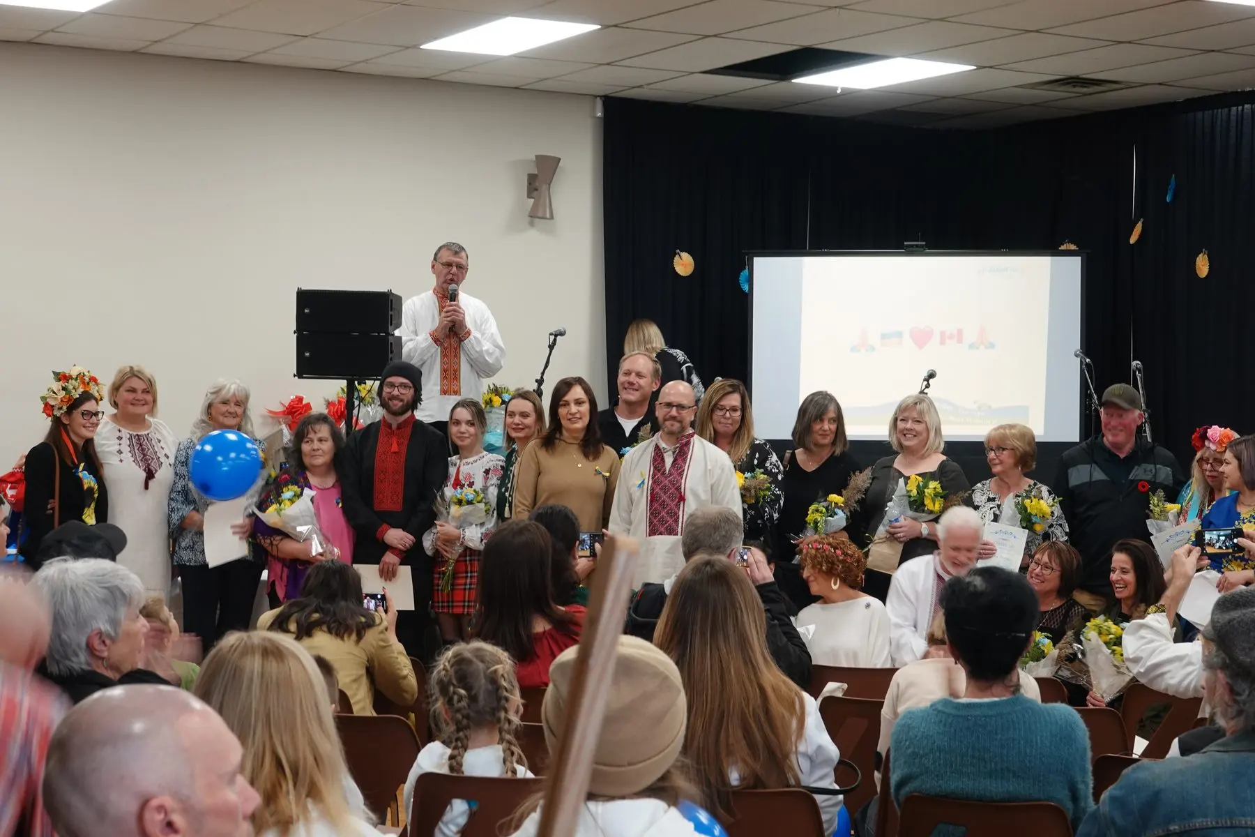 Organizers, volunteers and community partners of Ukrainian Fest Lanark County gathered at a community celebration, holding flowers and certificates