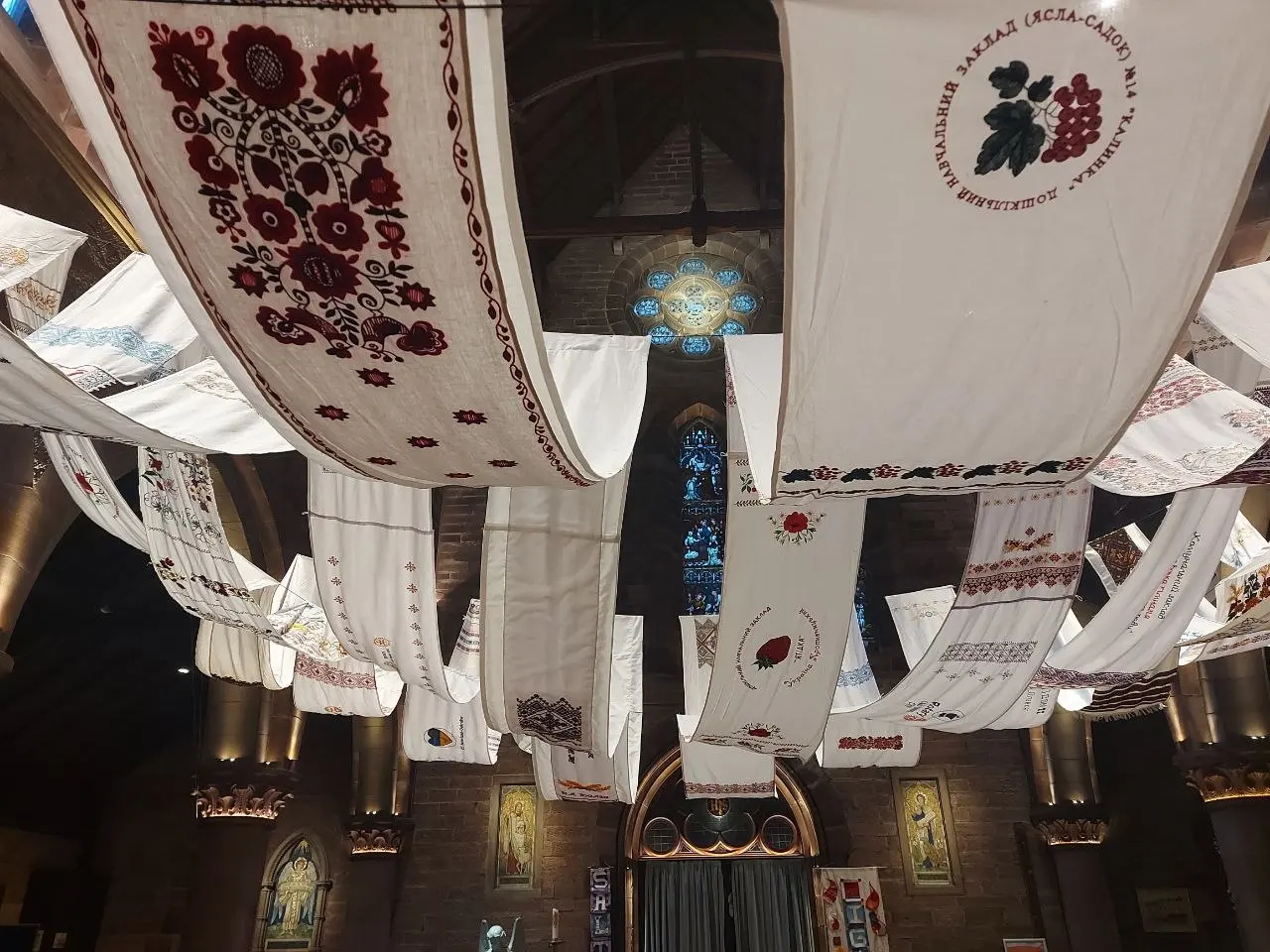 The collective rushnyk hanging across a stone church nave