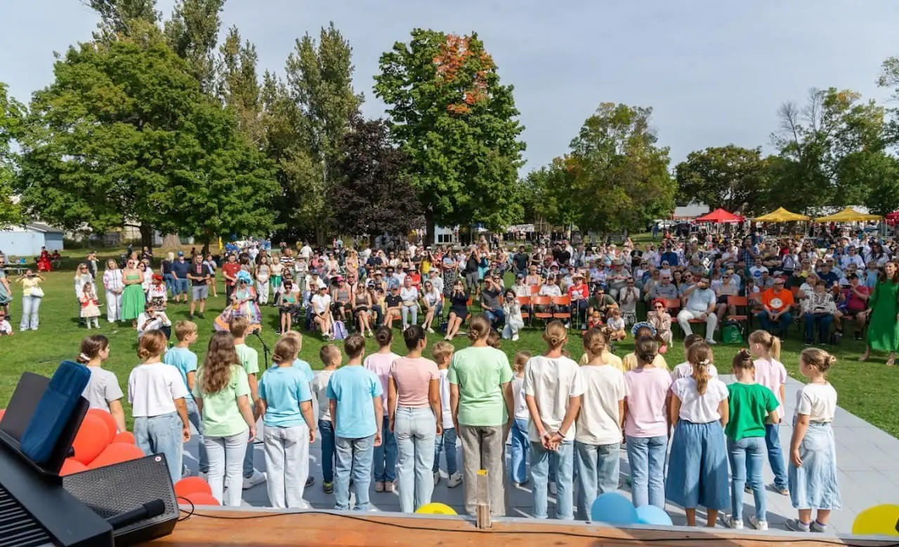 View from behind the UAFest main stage over a children's choir facing the festival crowd that fills the lawn at Riverside Park
