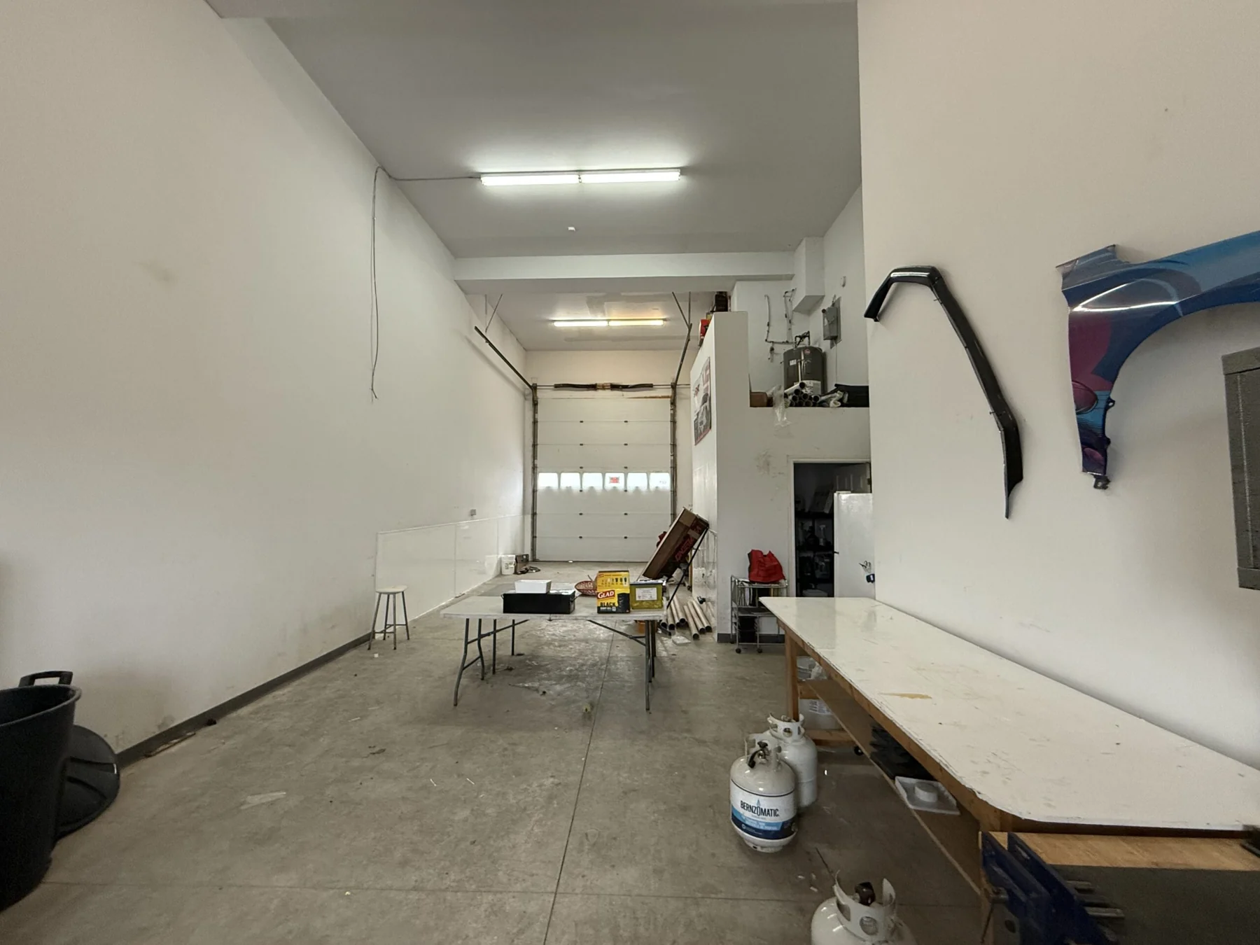 The length of the garage bay looking towards the closed overhead door, with a long work table along the right wall