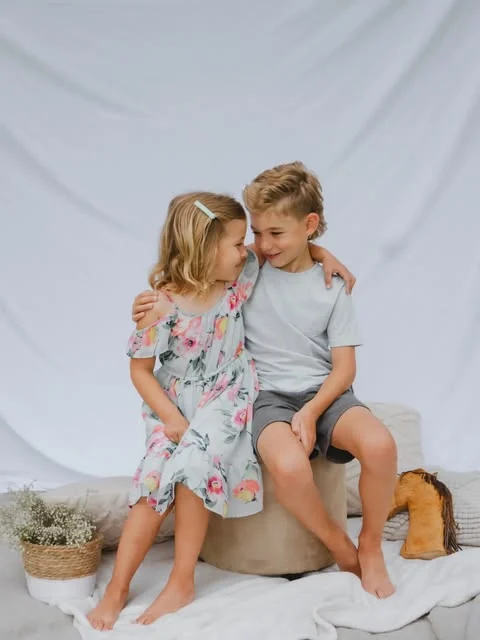 A studio frame of hers — a brother and sister sitting arm in arm on a low stool against a plain pale backdrop