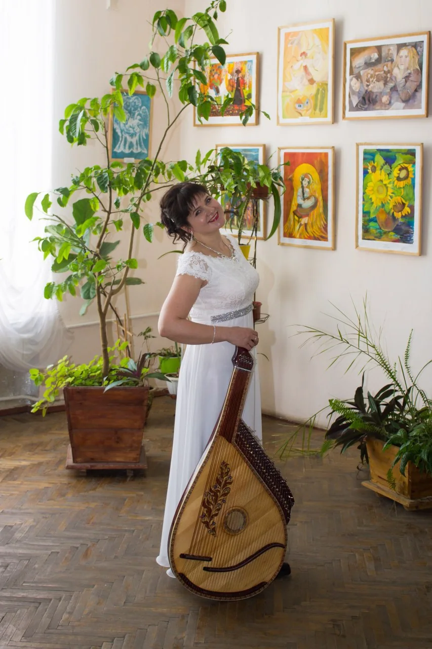 Lidiia Hurinenko with her bandura in a hall hung with paintings