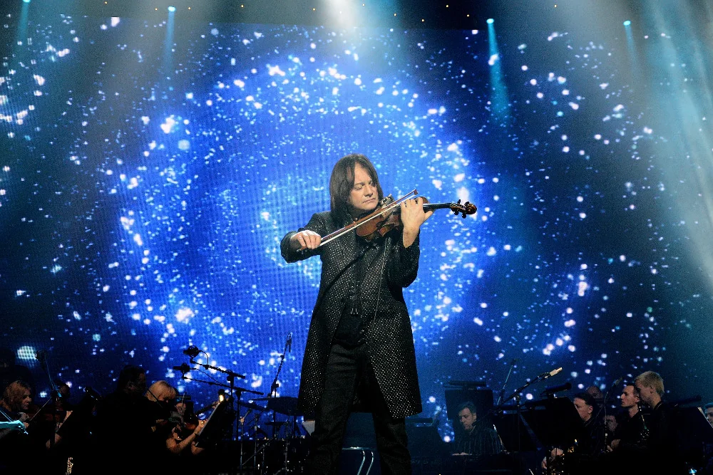 Vasyl Popadiuk performing on a concert stage under a starry blue spiral projection
