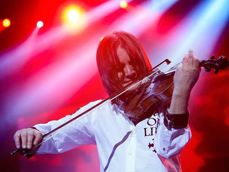 Vasyl Popadiuk in a white shirt, playing under red and blue stage lights
