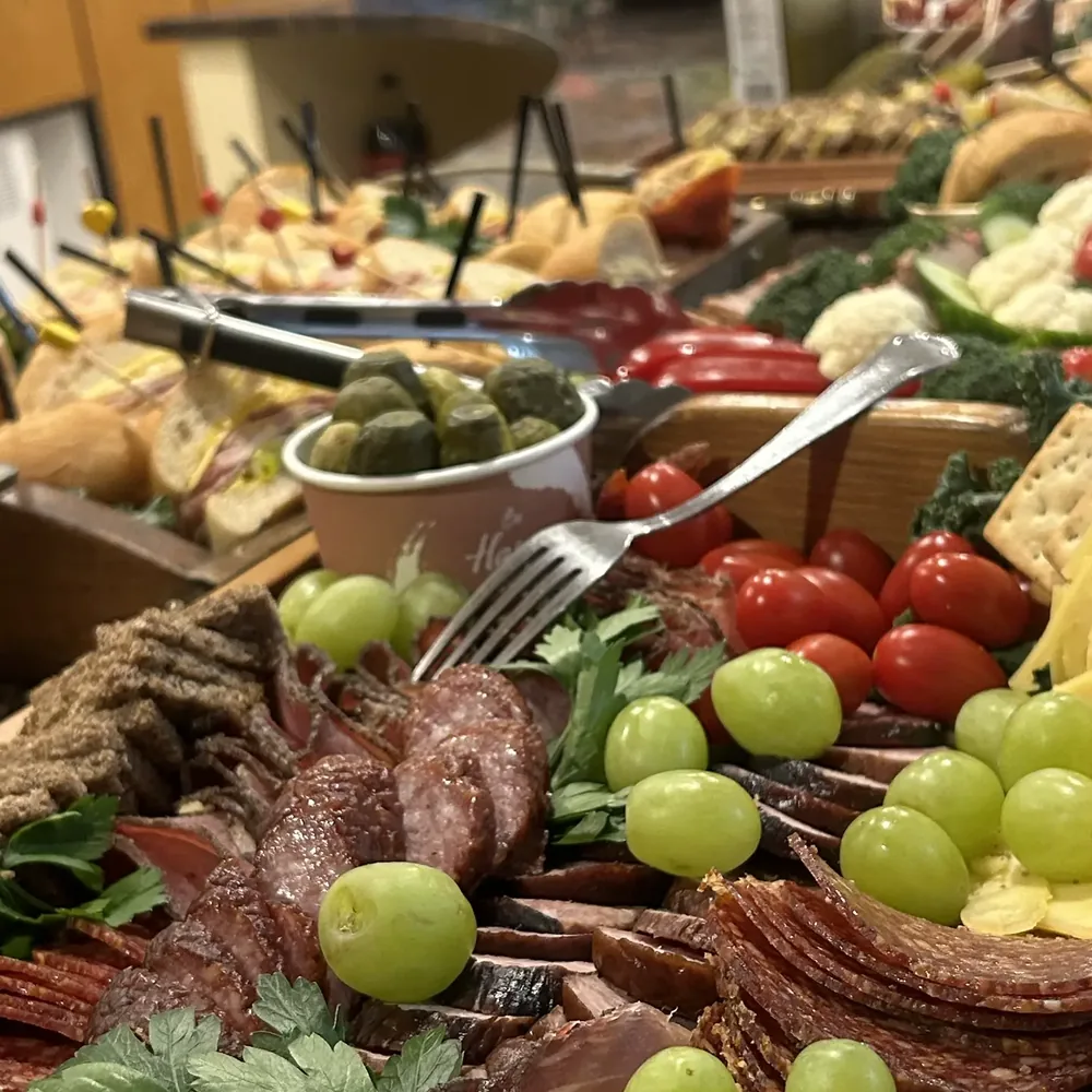A Wedel catering table laid with charcuterie boards, sandwiches, cheeses and vegetable platters